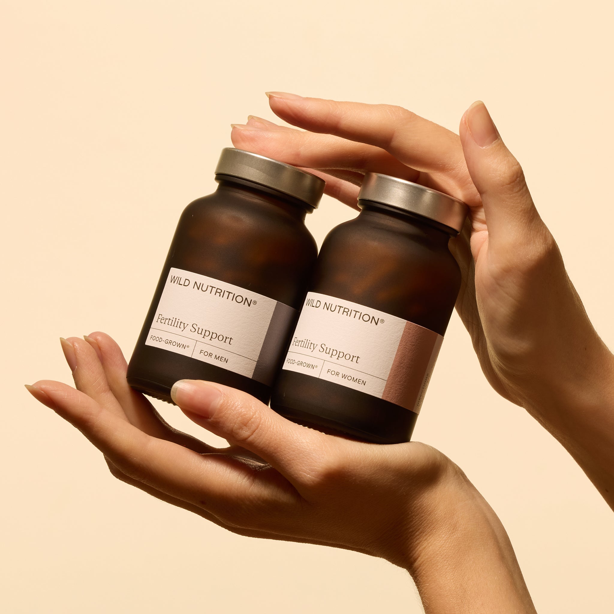 Hand holding women and men's fertility support supplement jars