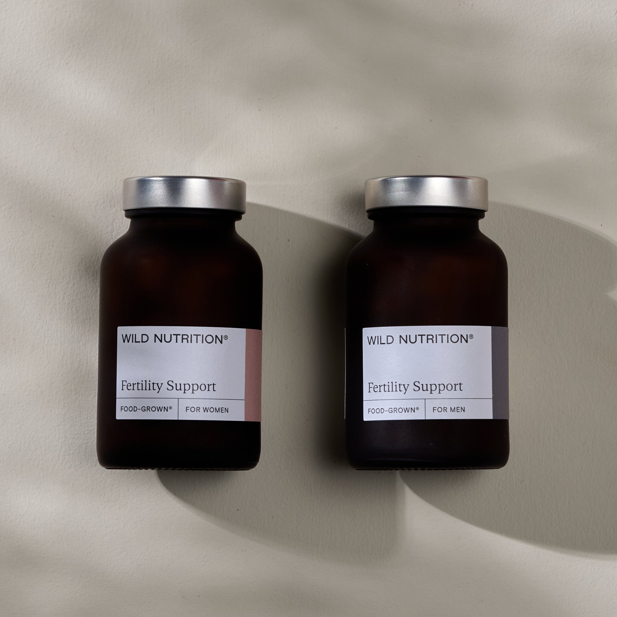 Women and Men's fertility supplement duo jars on a pain background