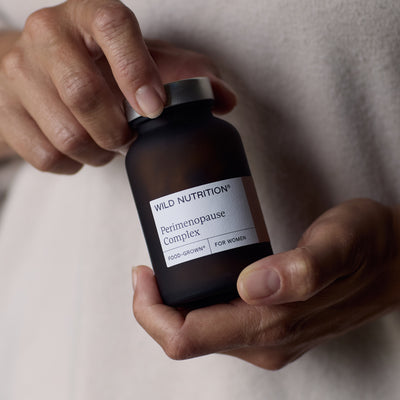 Hand holding a jar of perimenopause complex supplements