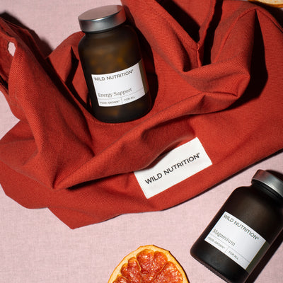 Two bottles of Wild Nutrition supplements on a red fabric background with an orange.