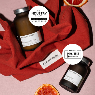 Two bottles of Wild Nutrition supplements (collagen and magnesium) on a red fabric background with 'The Industry Beauty' and 'Best Buy Indy' labels.