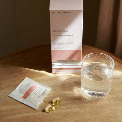 Daily essentials for women's fertility - open sachet, box and glass of water