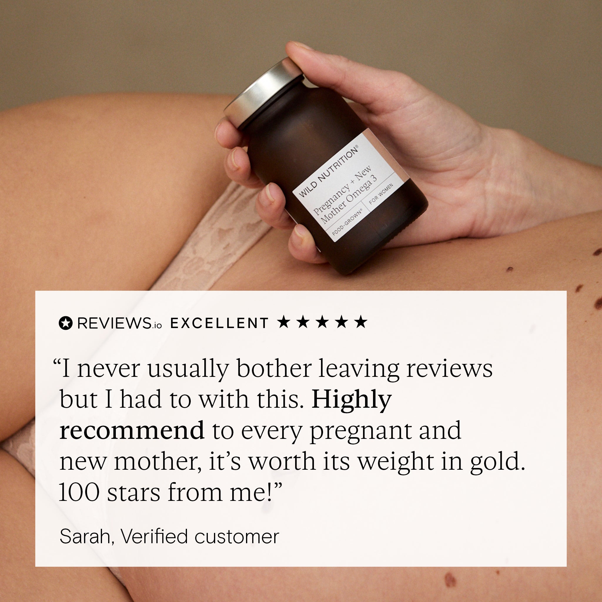 Hand holding a jar with a customer review overlay on a beige background. Review is for wild nutrition pregnancy omega 3 supplement.