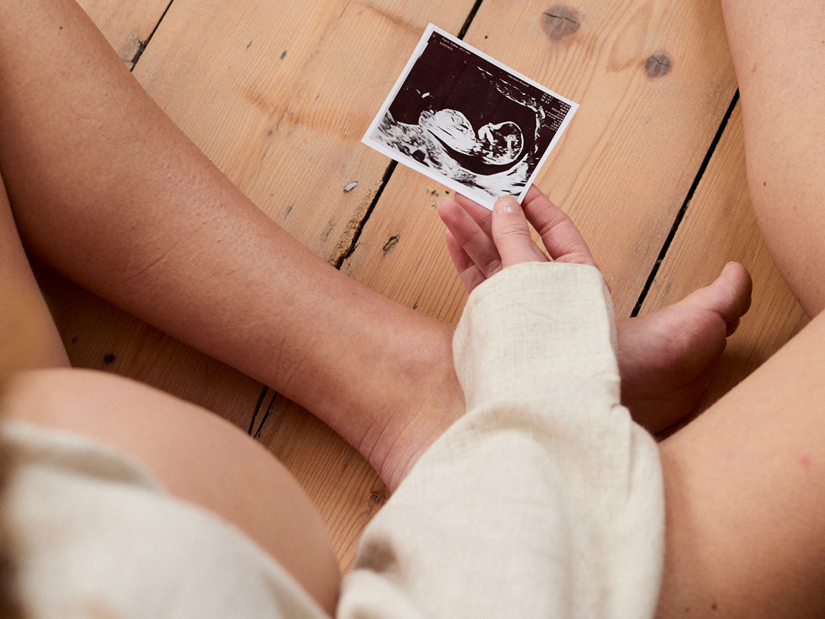 Pregnant woman holding an ultrasound image on a wooden floor