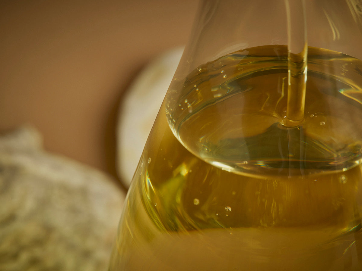 Close-up of a glass container with omega 3 oil being drizzled into it.