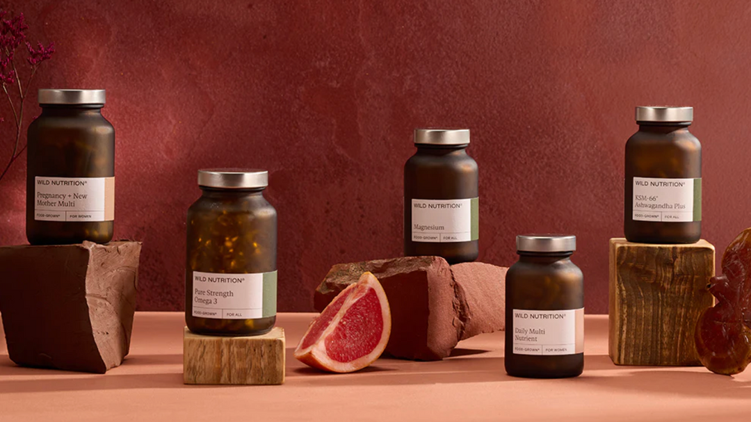 Jars of Wild Nutrition products on a wooden surface with a red-brown background
