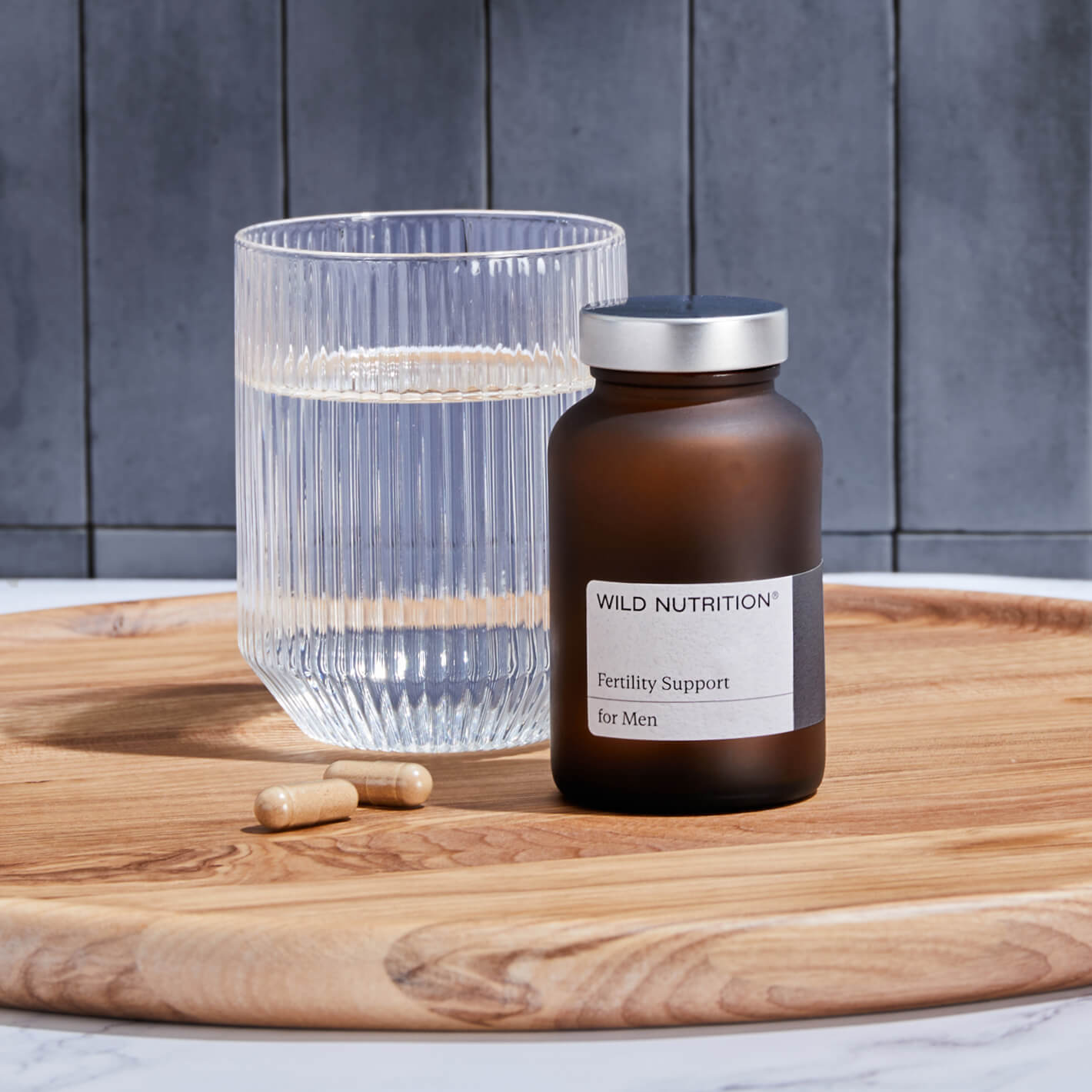Men's Fertility Duo with water glass and capsules, supporting testosterone and seminal health for fatherhood.