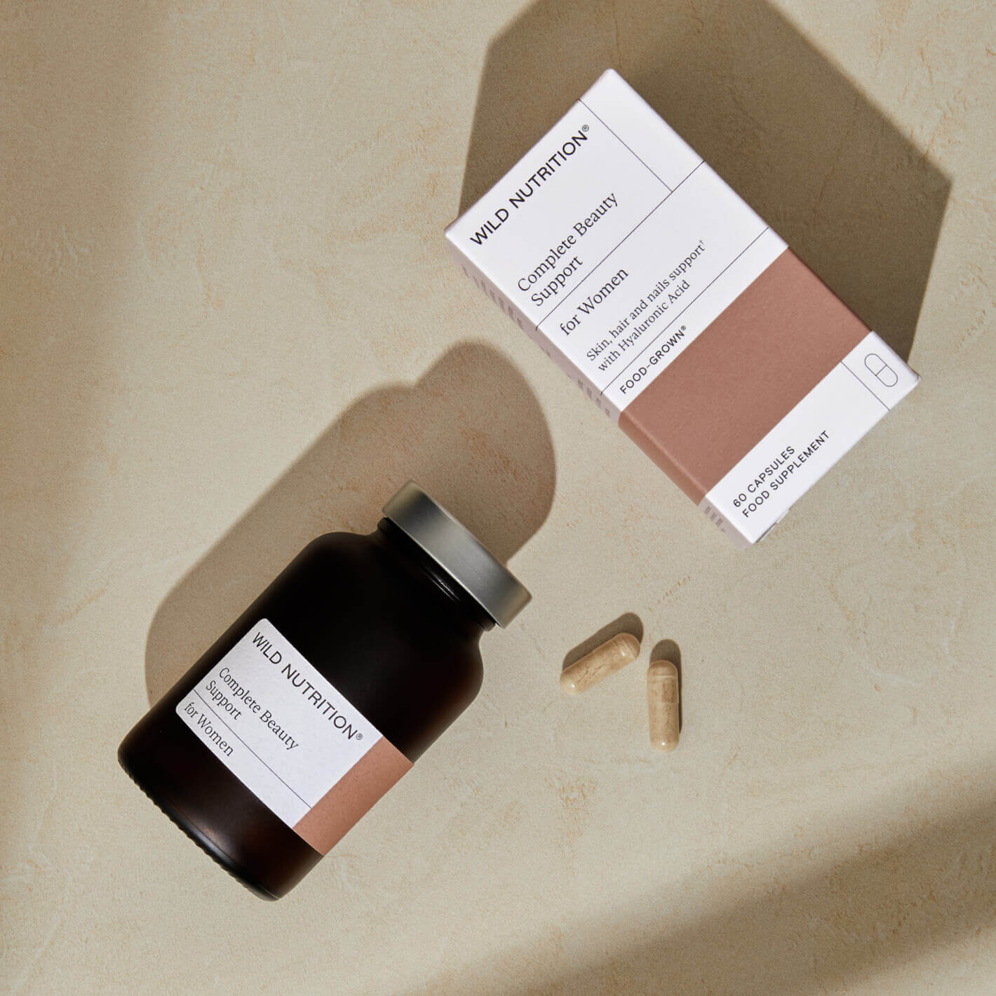 Wild Nutrition Complete Beauty Supplement for Women with capsules and packaging on a light surface.