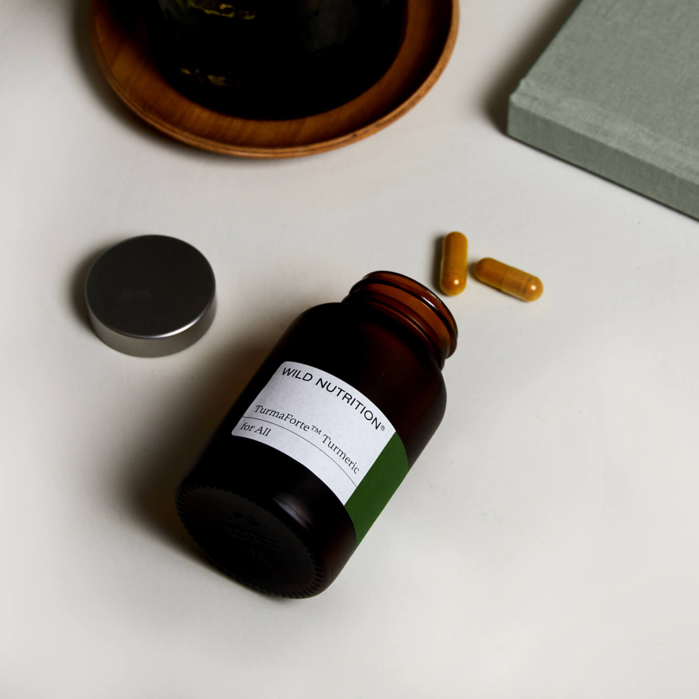 Bottle of Wild Nutrition Turmeric capsules for joint and bone support, with two capsules on a table.