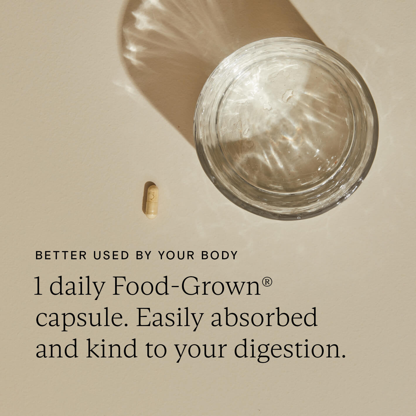 Daily Food-Grown capsule beside a clear glass of water, highlighting easy absorption and gentle digestion support.