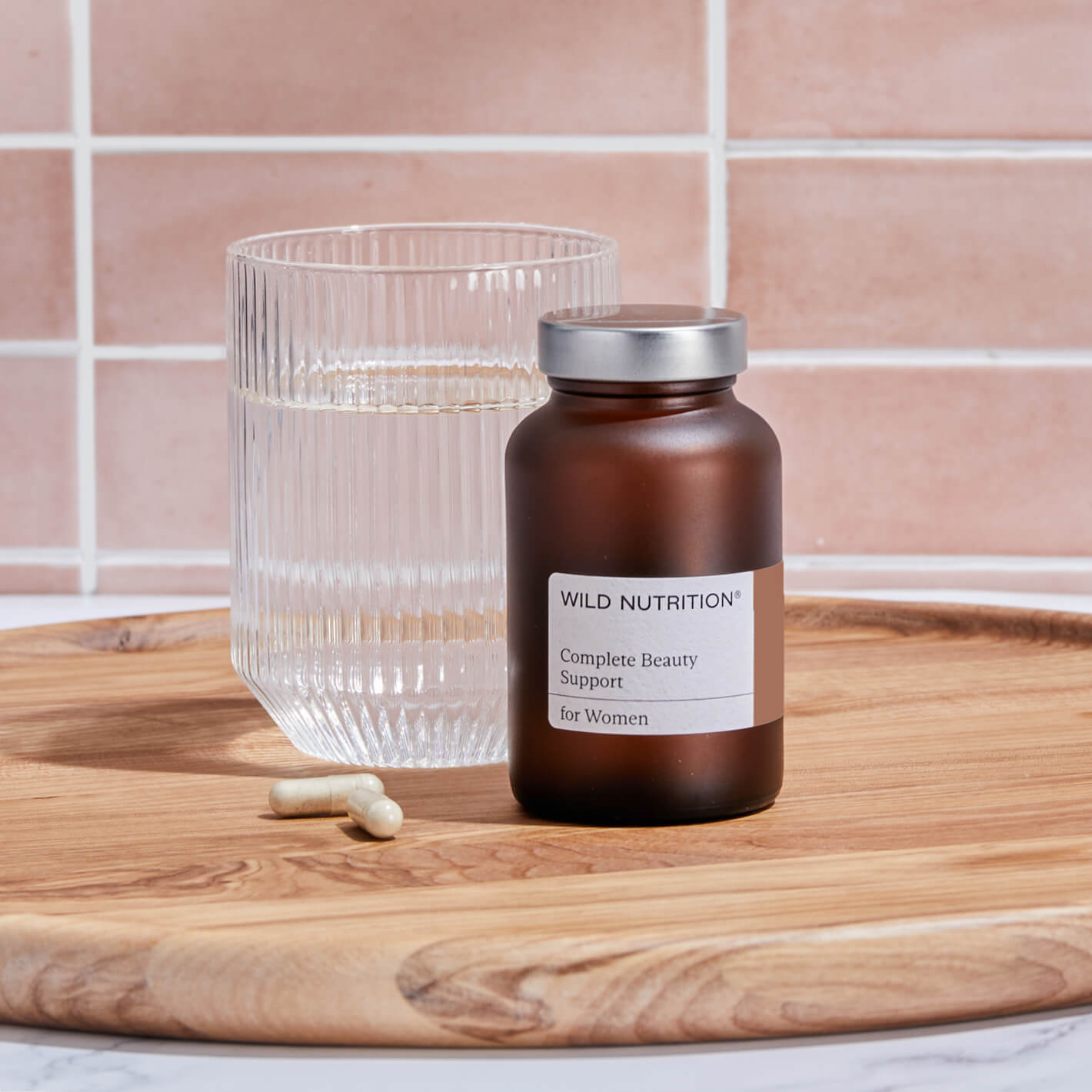 Wild Nutrition Complete Beauty Support for Women with water glass on a wooden platter, promoting skin health and nourishment.